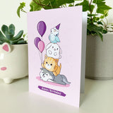 Illustrated pink birthday card featuring adorable animals celebrating.