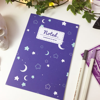 Notebook with celestial pattern of moons and stars on the cover.