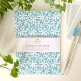 A6-sized notebook with a daisy flower pattern on the cover.