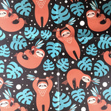Wrapping paper with cartoon sloths hanging from green leaves pattern.
