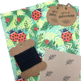 Eco-friendly wrapping paper with ladybird patterns, includes tags and string.