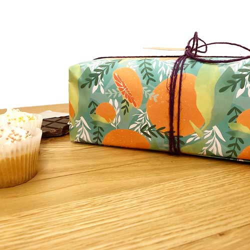 Bright orange-themed, eco-friendly gift wrap with Tropicana fruit patterns.
