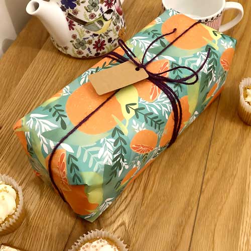 Bright orange-themed, eco-friendly gift wrap with Tropicana fruit patterns.