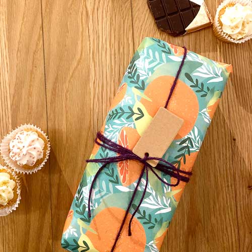 Bright orange-themed, eco-friendly gift wrap with Tropicana fruit patterns.